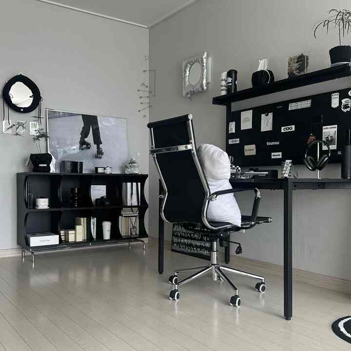 A modern study with black and white tones, featuring a black desk, office chair, and bookshelf in a home office setting