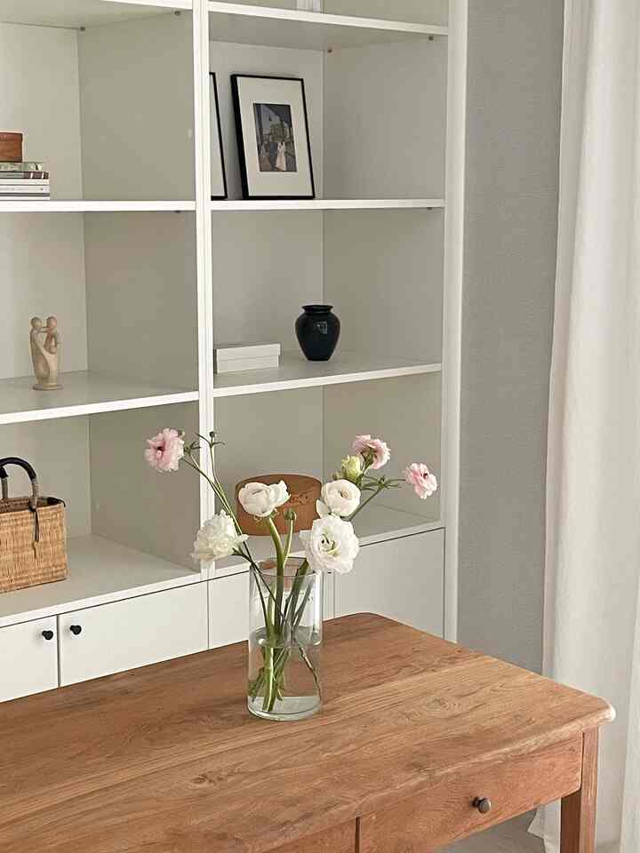 Natural wood tones and white study featuring a wooden desk with a vase of flowers centered, creating a cozy atmosphere