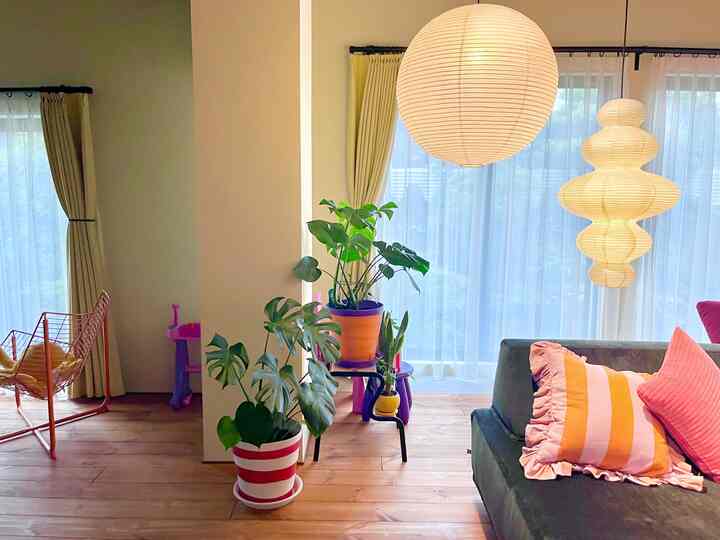 ネイビーのソファと黄色いカーテンがある自然光あふれるリビング、木目調の床と植物が調和した雰囲気のあるインテリア