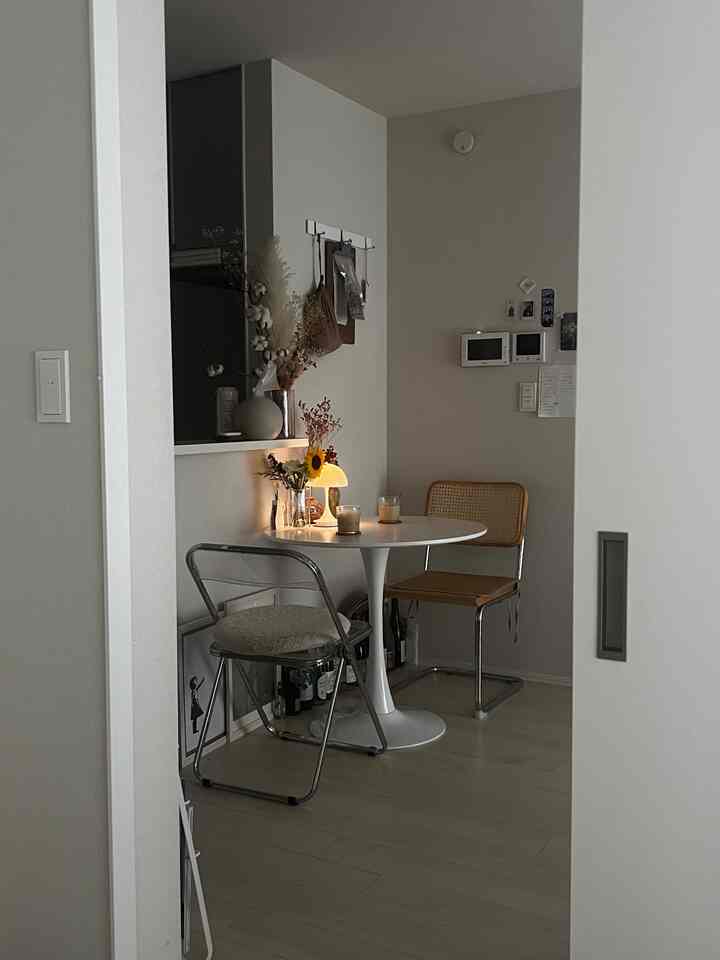 白とナチュラルカラーのコンパクトなダイニングスペース、丸テーブルとシンプルな椅子、暖かなテーブルランプが印象的な雰囲気を醸し出しています。