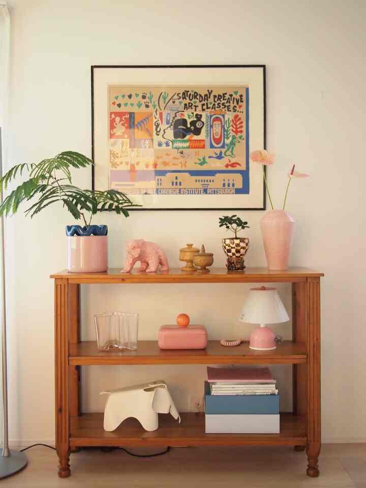 ピンクと木目調が調和する棚とアートが配置された雰囲気のあるヴィンテージ風インテリア