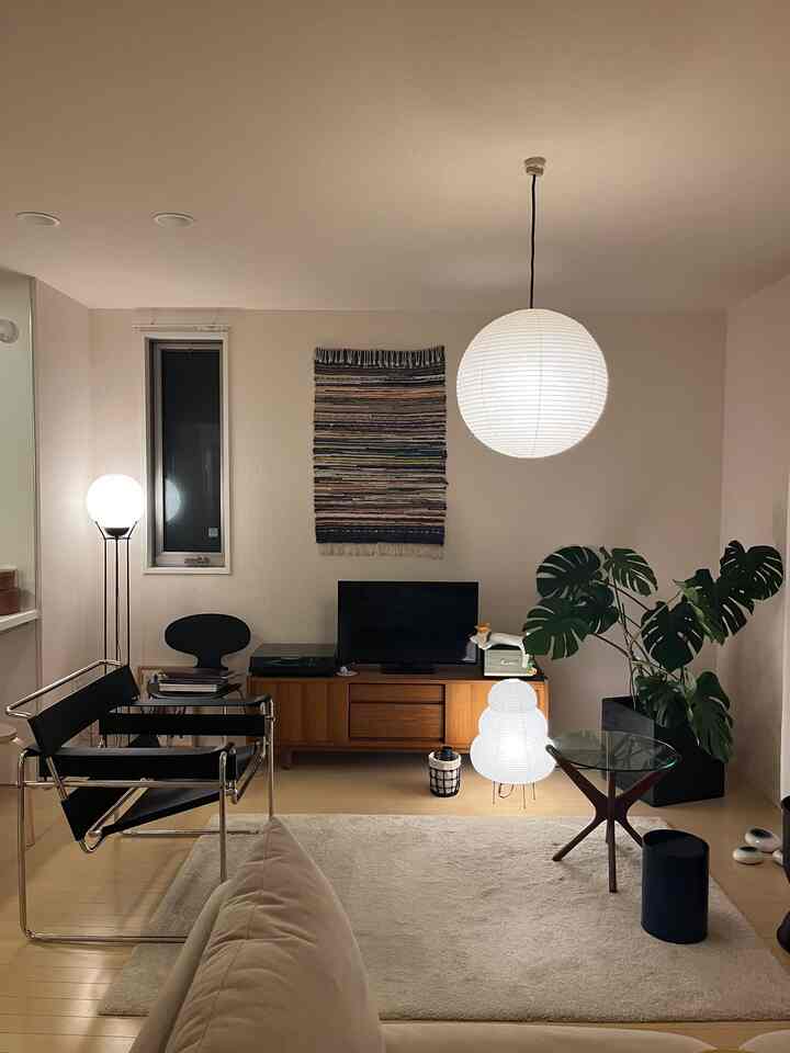 ナチュラルな色調のリビング、中央にペンダントライトと自然素材の家具が配置された落ち着いたインテリア