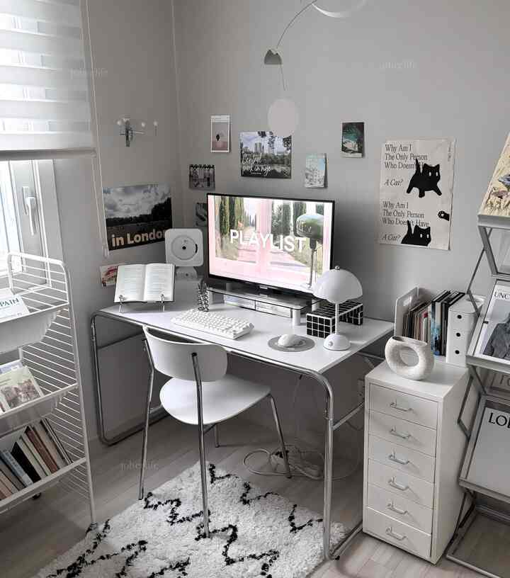 白とシルバーの色調の書斎、デスクとパソコンのモニター、本棚、照明が配された印象的な作業空間