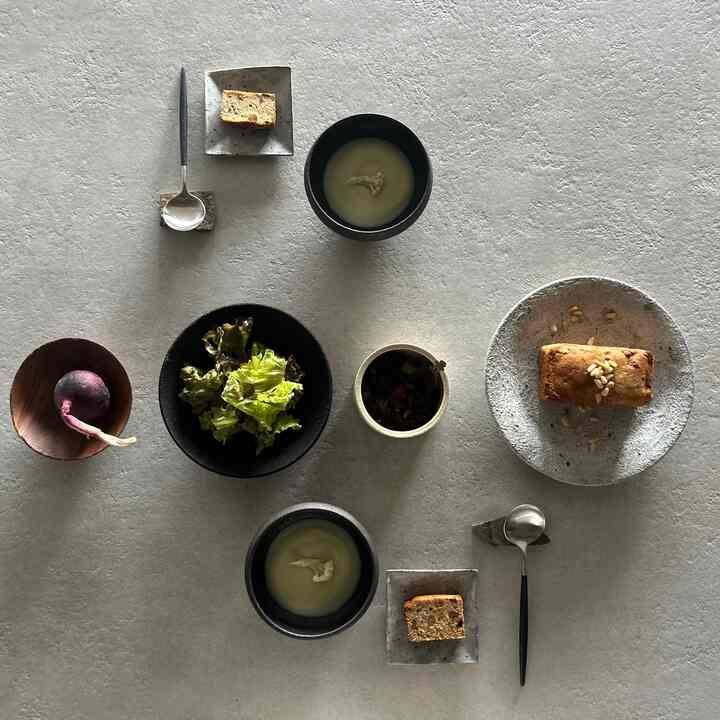 ベージュ調のダイニングテーブルに和食器、新鮮な季節の野菜と薬膳ケーキが調和した雰囲気のあるナチュラルモダンなおうちカフェ