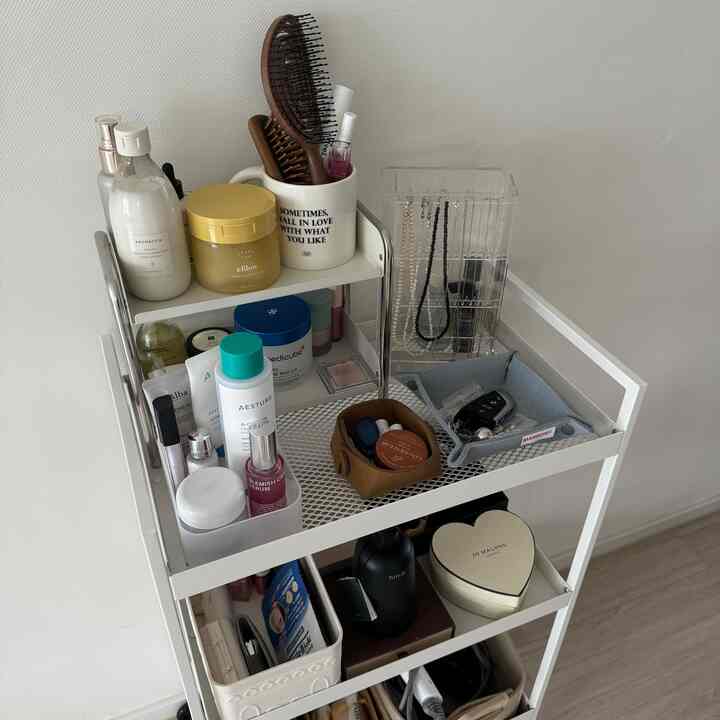 白色調の収納棚に化粧品や小物、透明なアクリル製のネックレス収納が整えられた清潔感のあるインテリア