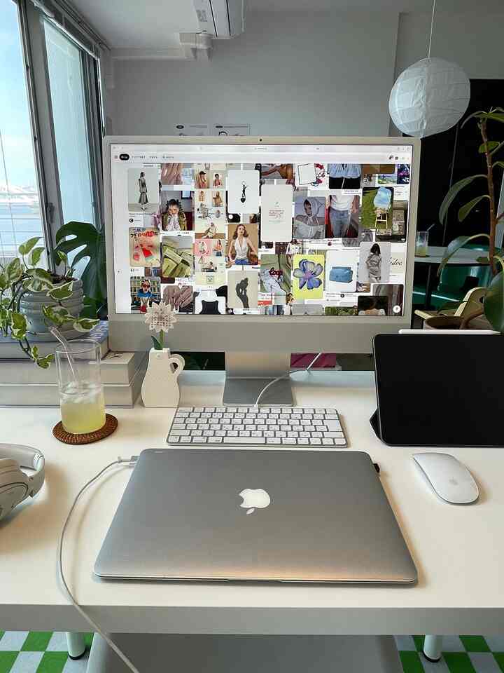 白と緑の色調が印象的なワンルームのホームオフィス、デスクにはコンピューターと植物が配置された清潔感のある空間