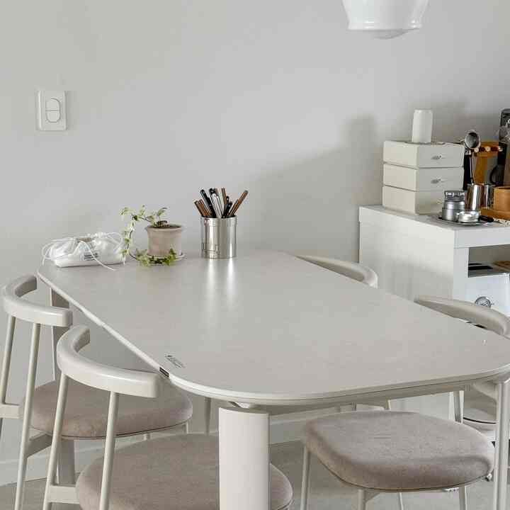 White and beige toned dining room featuring a simple dining table and chairs with a clean and minimal atmosphere