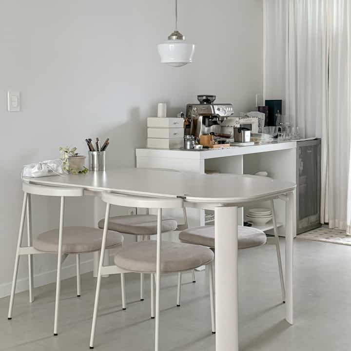 White-toned kitchen space featuring a ceramic dining table and chairs with a clean, modern atmosphere