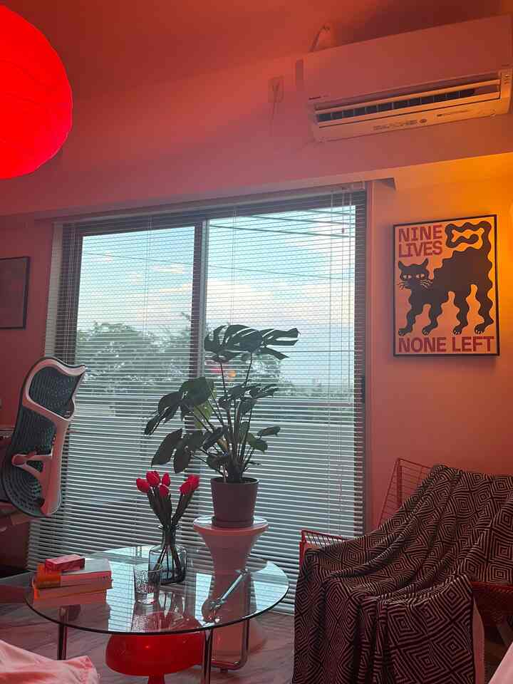 Red pendant light and mid-century modern furniture featuring a large monstera plant in a naturally lit living room space