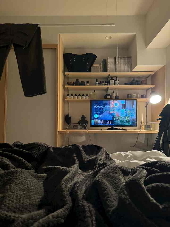 ホワイトとブラックのトーンの寝室、壁面にTVと小物が配置された雰囲気のあるモダンな空間