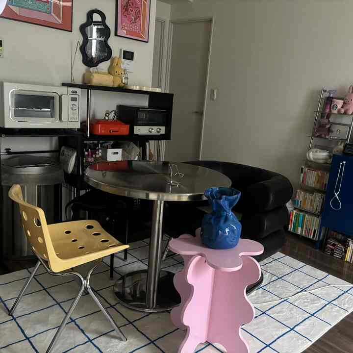 A modern dining room with white and black tones featuring a yellow chair and a pink flower-shaped table