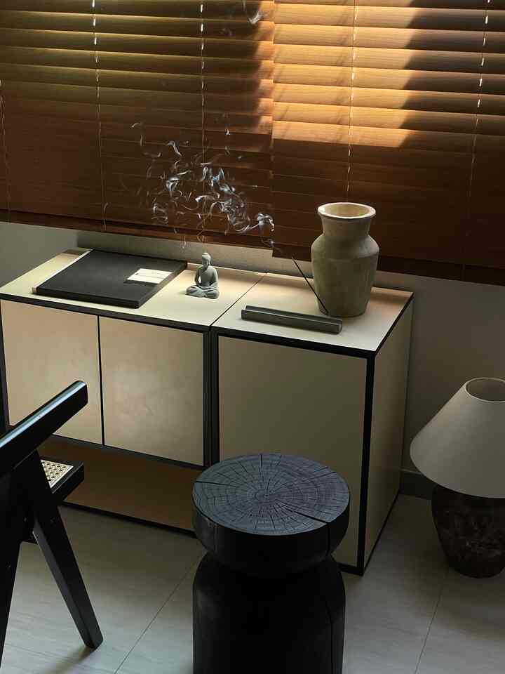 ウッドトーンとベージュの収納が配されたモダンな一人暮らしのリビング、香の煙が漂う落ち着いた雰囲気のインテリア