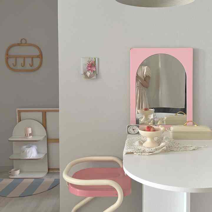 Minimal dressing room in ivory and pink tones featuring an arched mirror, table, and chair creating a cozy atmosphere
