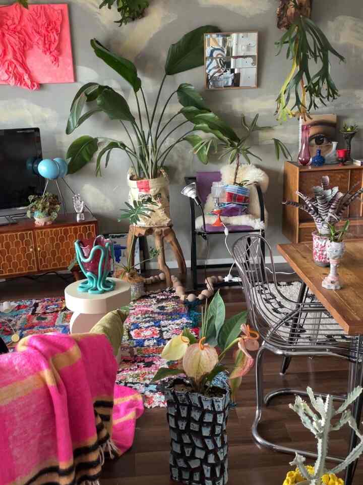 自然素材とカラフルな装飾が調和したボヘミアンスタイルのリビング、植物と木目調家具が配された雰囲気のあるインテリア