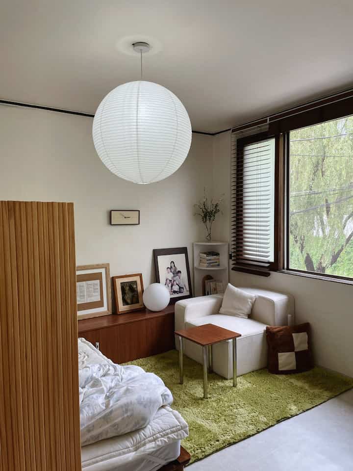 White and wood-tone living room by veranda featuring sofa and green rug with cozy atmosphere