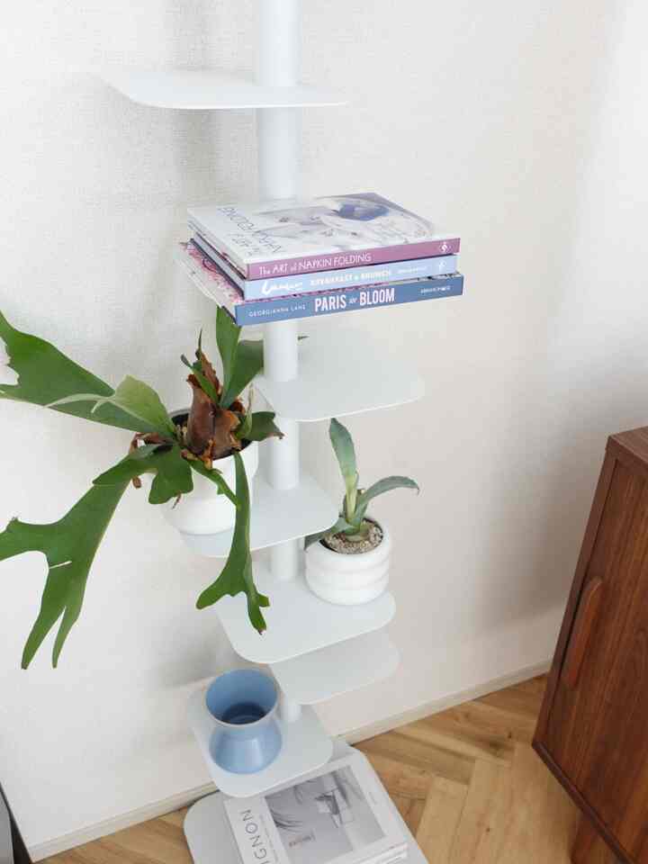 ホワイトと木目調が調和するコーナー収納棚と植物が配置されたシンプルでミニマルなインテリア空間