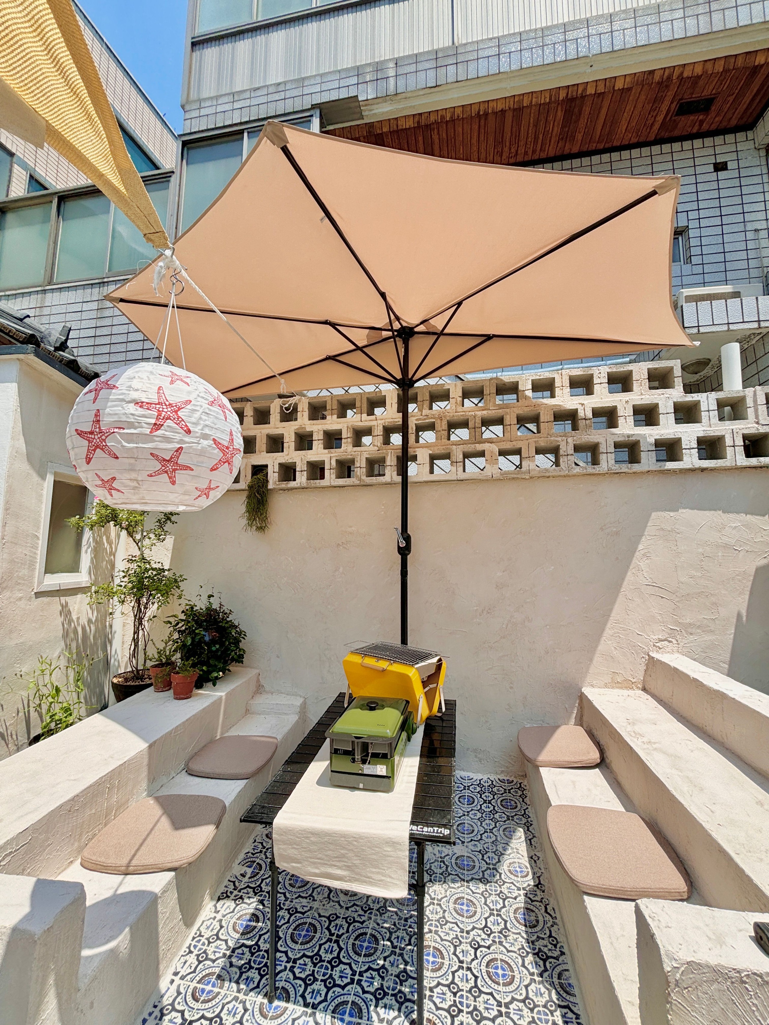 Large beige umbrella creating a defined shaded outdoor room over seating