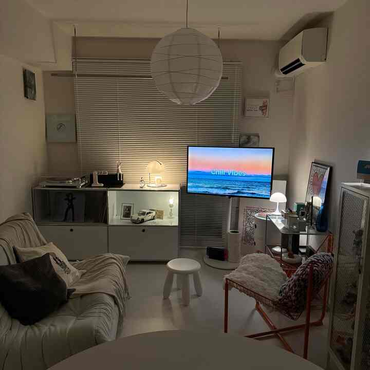 白を基調としたリビング、ソファとペンダントライト、テレビ台が配置された落ち着いた夜の空間