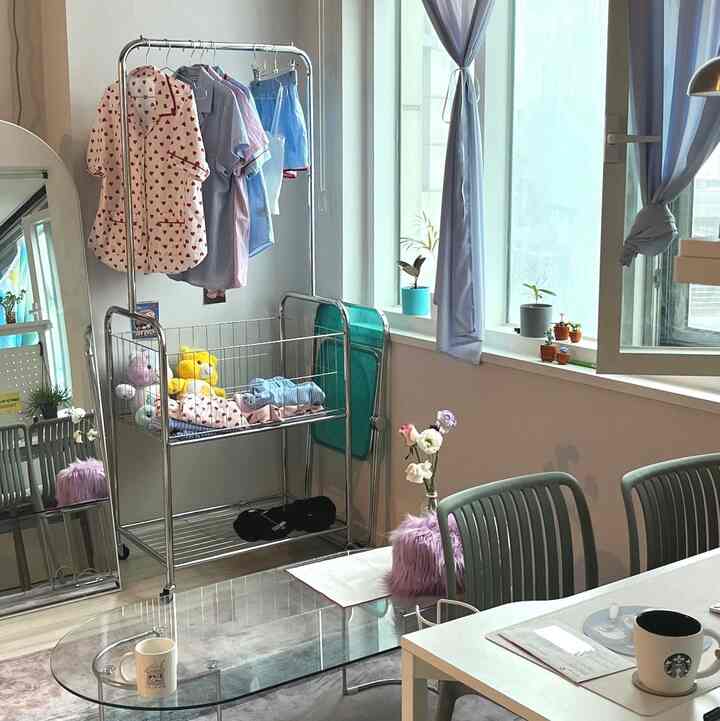 淡いピンクのラグと透明なガラステーブル、淡いブルーのカーテンが配置されたリビングの印象的な空間