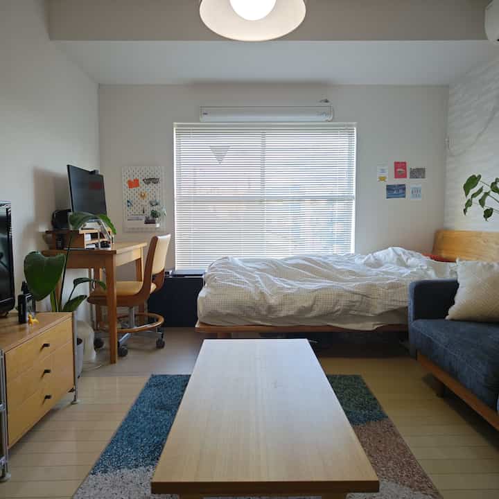 ナチュラルウッドトーンとブルーのラグがある一人暮らし向けの1K、7畳の落ち着いた清潔な空間