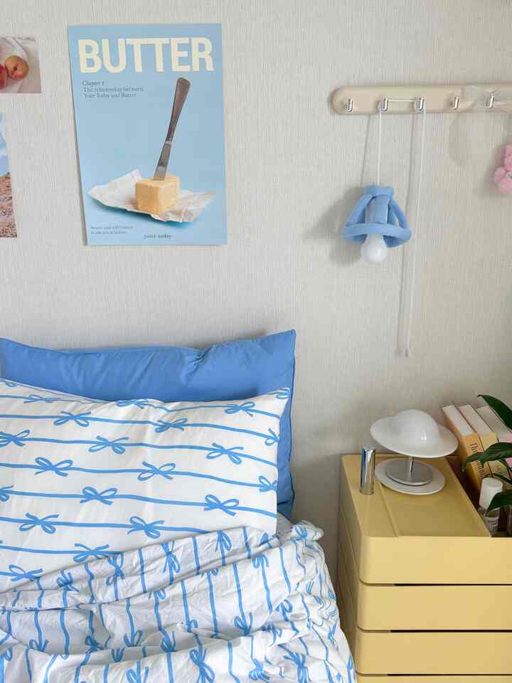 パステルイエローとブルーのトーンの寝室、枕と掛け布団カバーが配置された温かみのある空間