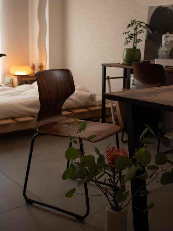 A warm brown and wood-toned single household bedroom featuring a stool and plants, exuding a natural modern calm atmosphere