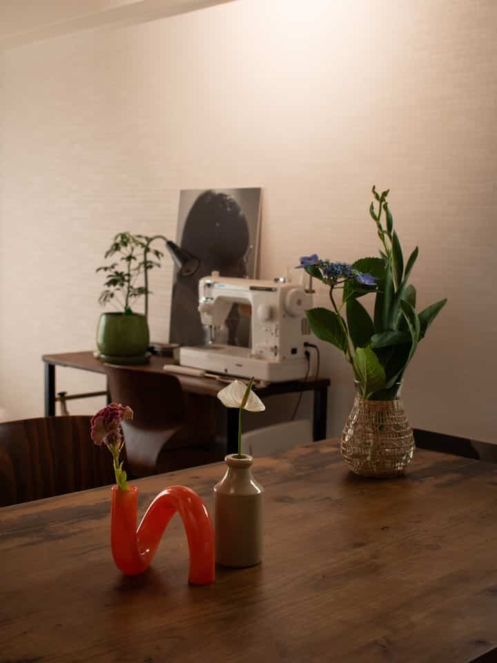 Natural-toned living room space featuring a wooden dining table with various vases and plants in a cozy interior