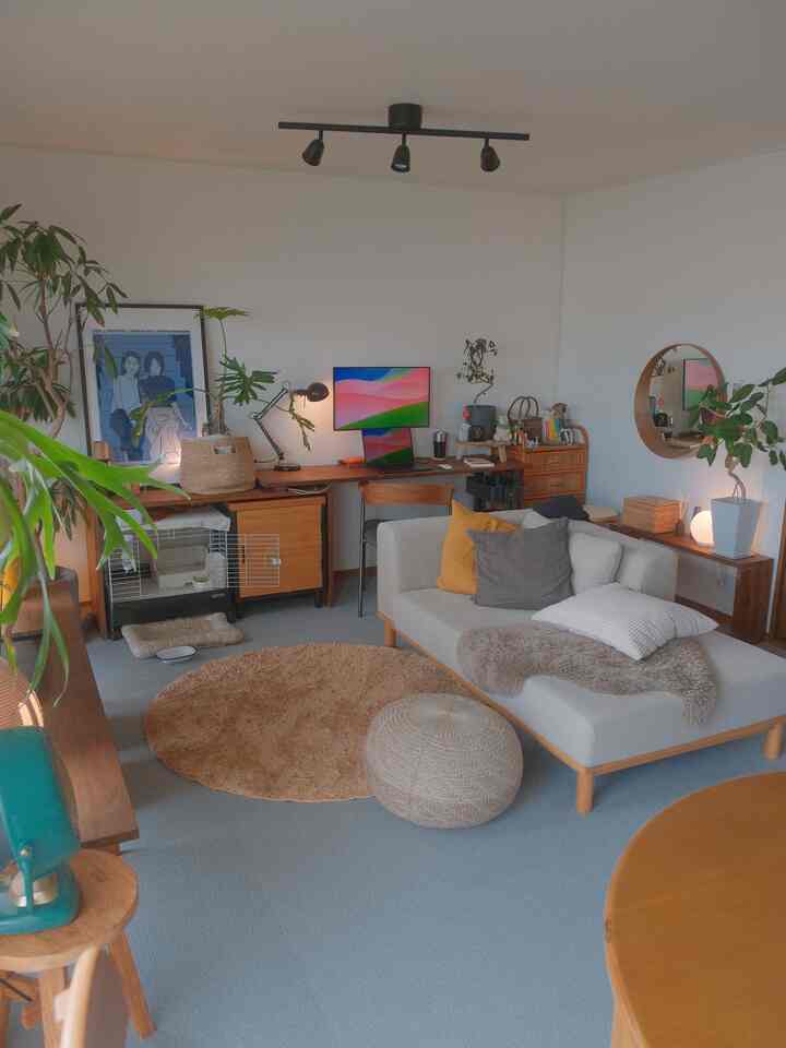 ナチュラルな色調の1LDKリビング、タイルカーペットの床とソファ、丸いラグが配置された雰囲気のある空間