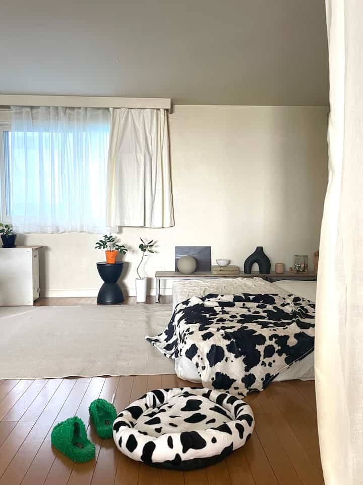 ベージュとウッドトーンの調和した寝室、ペットベッドと植物が配置された雰囲気のある空間