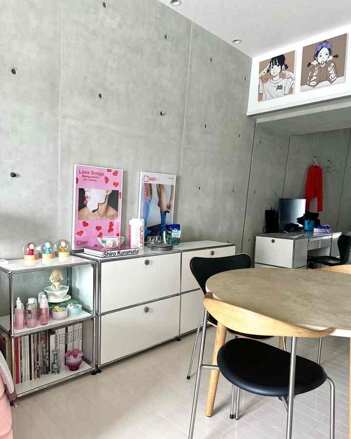 グレーのコンクリート壁と白い収納があるモダンなダイニング、木製のダイニングテーブルと黒いカールハンセン＆サンの椅子が配置された印象的な空間