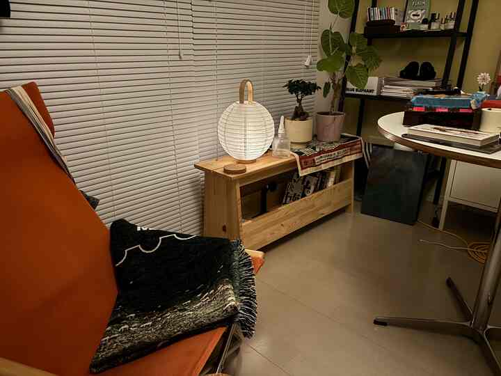 Beige-toned balcony featuring natural wood bench and orange sofa with a cozy atmosphere