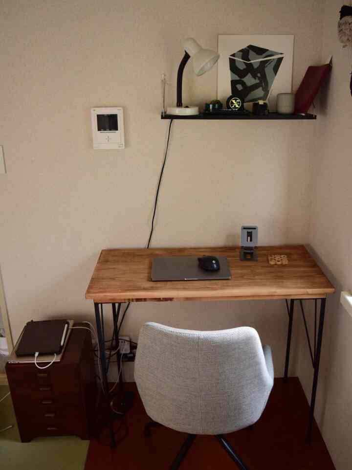 Natural wood tone compact home office corner featuring a gray office chair with a functional desk setup