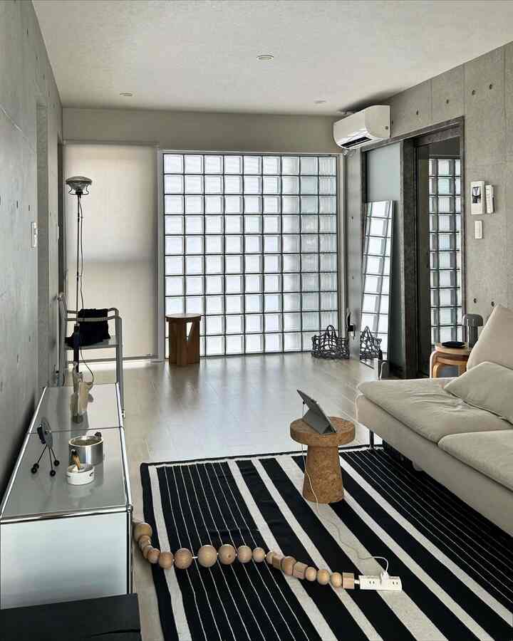 ライトグレーの壁とナチュラルな木調家具が配置されたモダンなリビング、ミニマリズムと余白を生かした印象的な空間