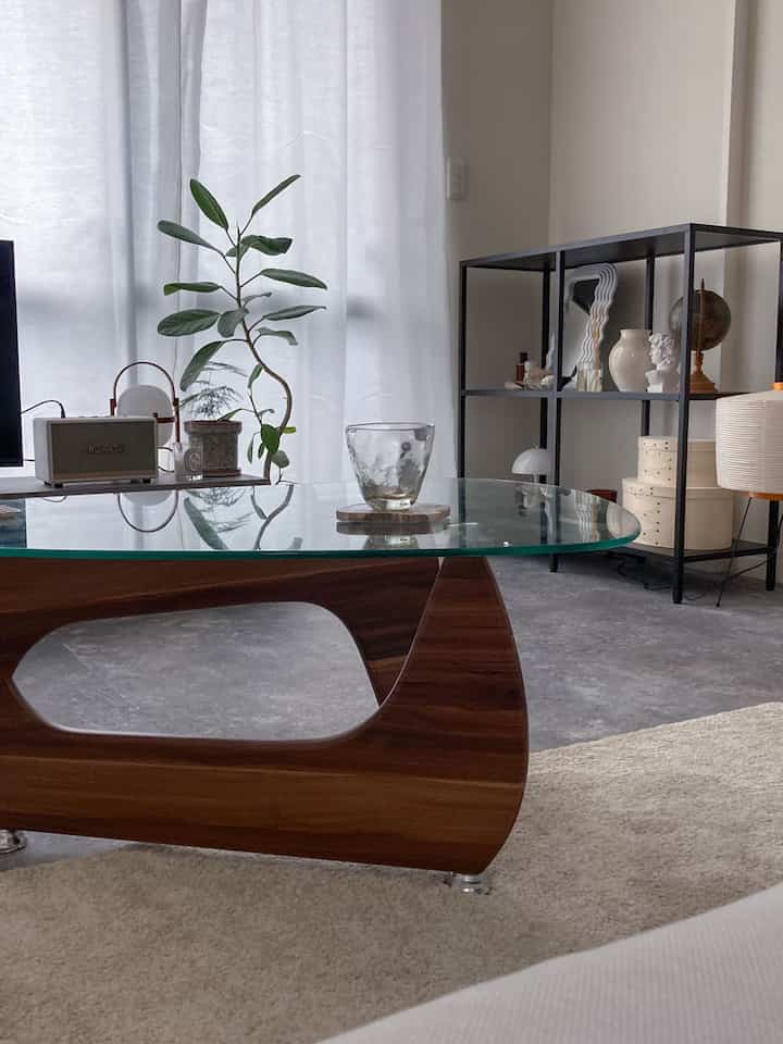 モノトーンとナチュラルウッド調のリビング、ガラスのダイニングテーブルとシンプルな棚が配された印象的な空間