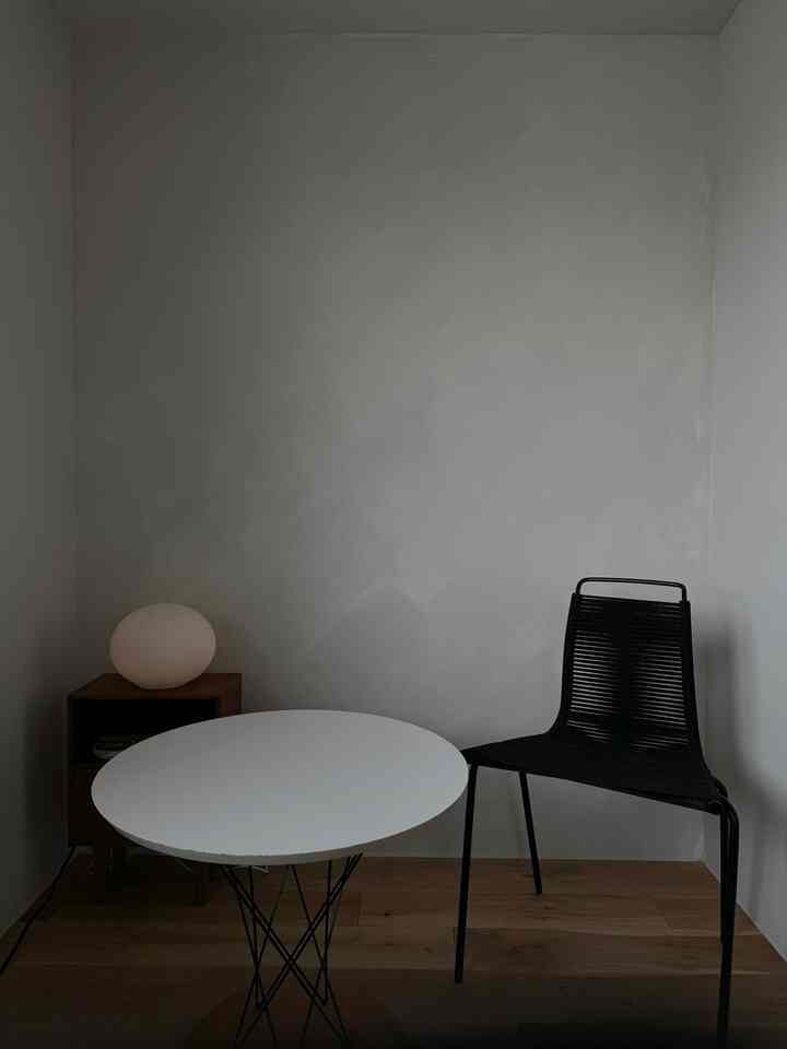 白と黒のトーンのダイニング、サイドテーブルとテーブルランプが配置されたシンプルモダンな印象的な空間