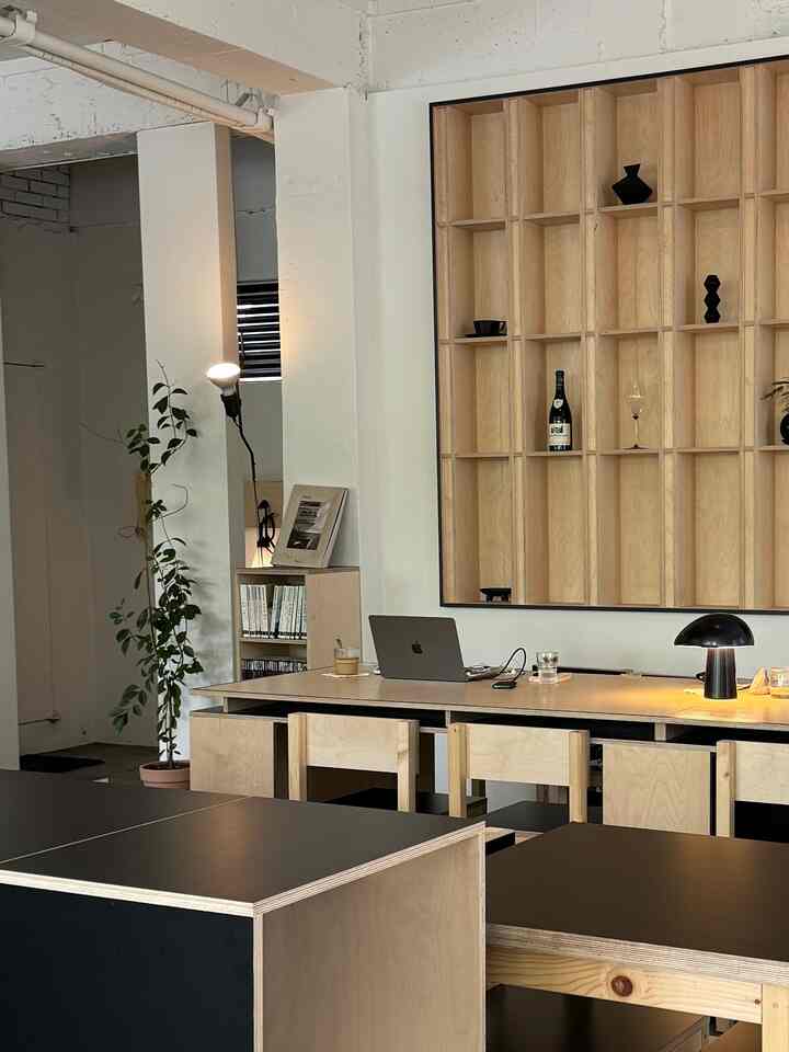 ミニマルで黒と木目調が調和したホームオフィス、植物とデザイナーズ照明が配置された落ち着いたインテリア