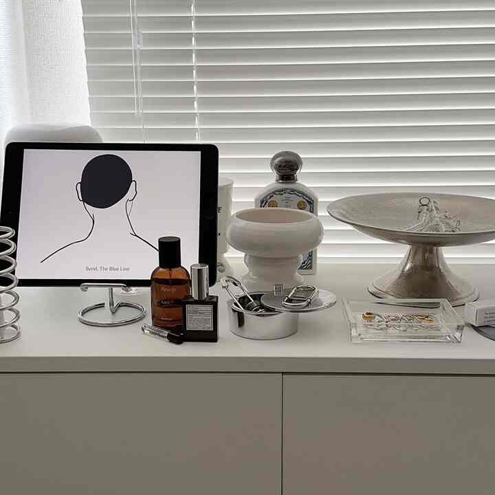 ホワイトトーンの寝室キャビネットに整然と並べられた小物が特徴のミニマルな雰囲気のインテリア