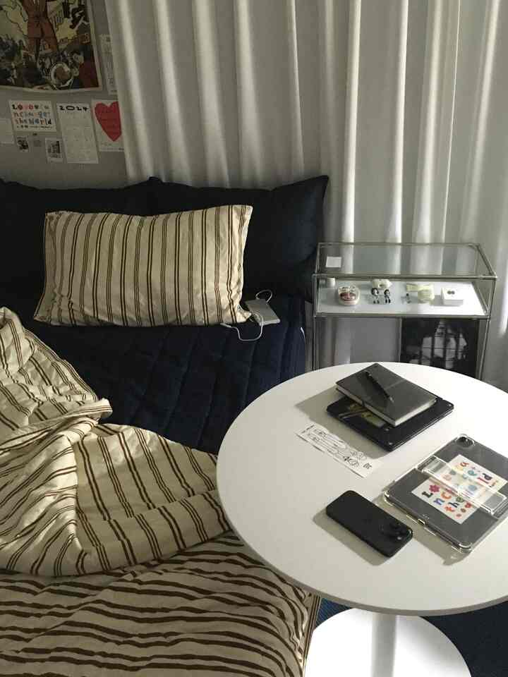 ネイビーとホワイトの寝室、ストライプの寝具とミニマルな丸テーブルが配置されたモダンなインテリア