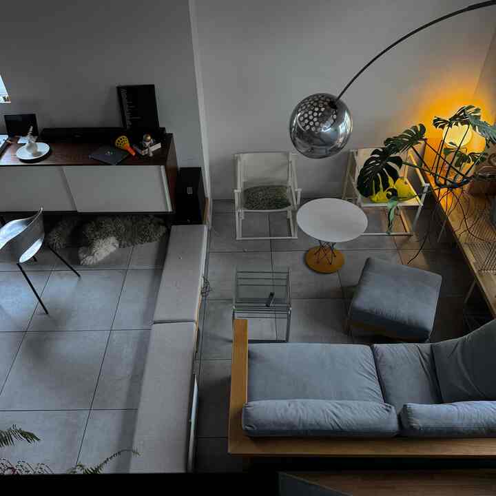 グレーと木目調のモダンなリビング、ソファや椅子、フロアランプが配置され、温かみのある雰囲気のあるインテリア