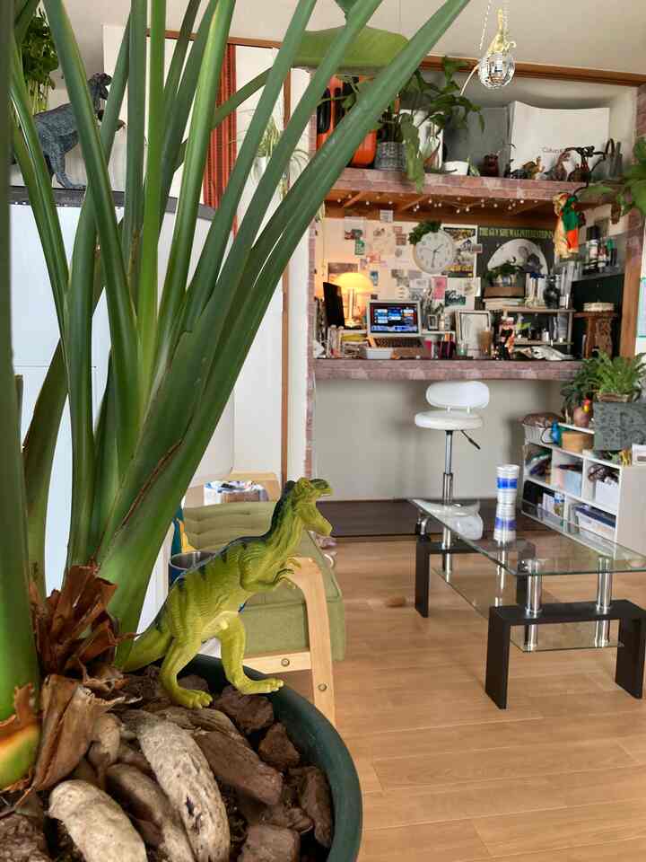 Natural tone compact living room featuring green plants and vintage furniture with a cozy atmosphere