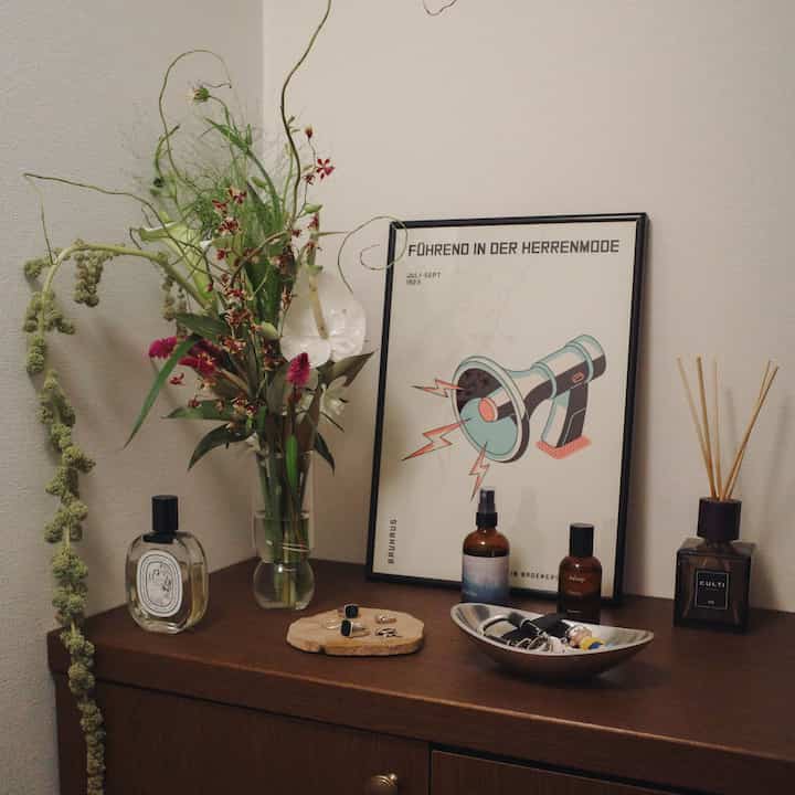 Natural tone entrance space featuring a wood tone storage cabinet with vase, diffuser, and simple decor accessories