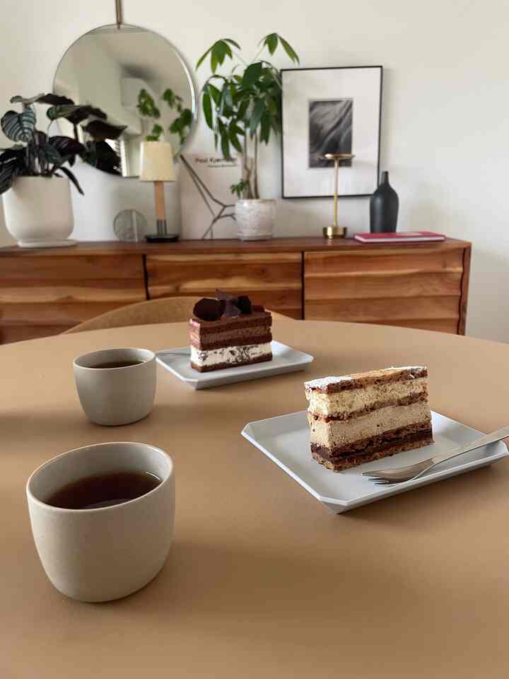 ベージュカラーのテーブルにケーキと紅茶が置かれた、温かみのあるおうちカフェの雰囲気あるインテリア