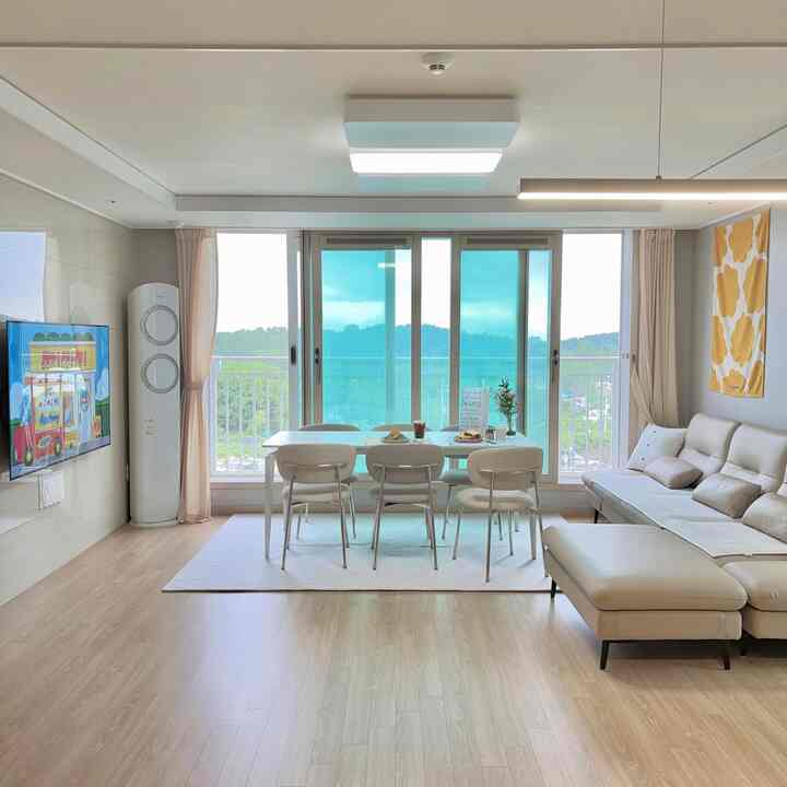 白とベージュの色調が調和したリビング、4人用のダイニングテーブルとソファが配された明るく広々とした空間