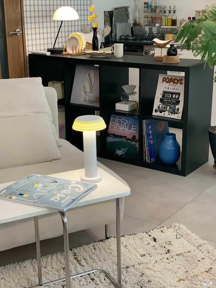 ダークブラウンとブラックのトーンが特徴のリビングとキッチン、IKEAのカラックス本棚が空間を仕切る、温かみのあるモダンなインテリア