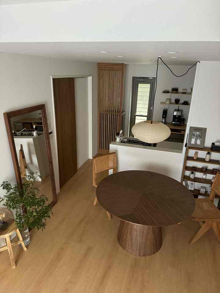 ナチュラルな木目調と和モダンスタイルのキッチンとダイニング、丸いダイニングテーブルと籐の椅子が配置された落ち着いた雰囲気のインテリア