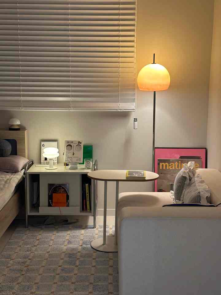 Light brown and beige toned bedroom featuring sofa, side table, and floor lamp in a cozy natural modern setting