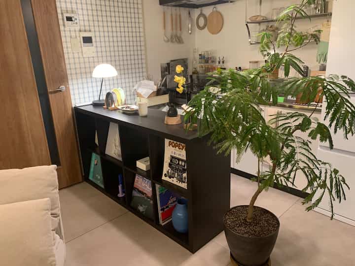 ナチュラルトーンとブラックの色調が調和したキッチンとリビングの連結空間、キッチンカウンターと食器収納が配置された雰囲気のあるインテリア