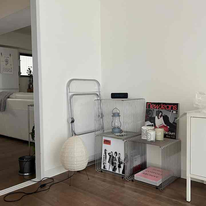 Modern living room with white walls and wood tone flooring, featuring minimalist metal shelves and simple lighting accessories for a clean, simple atmosphere