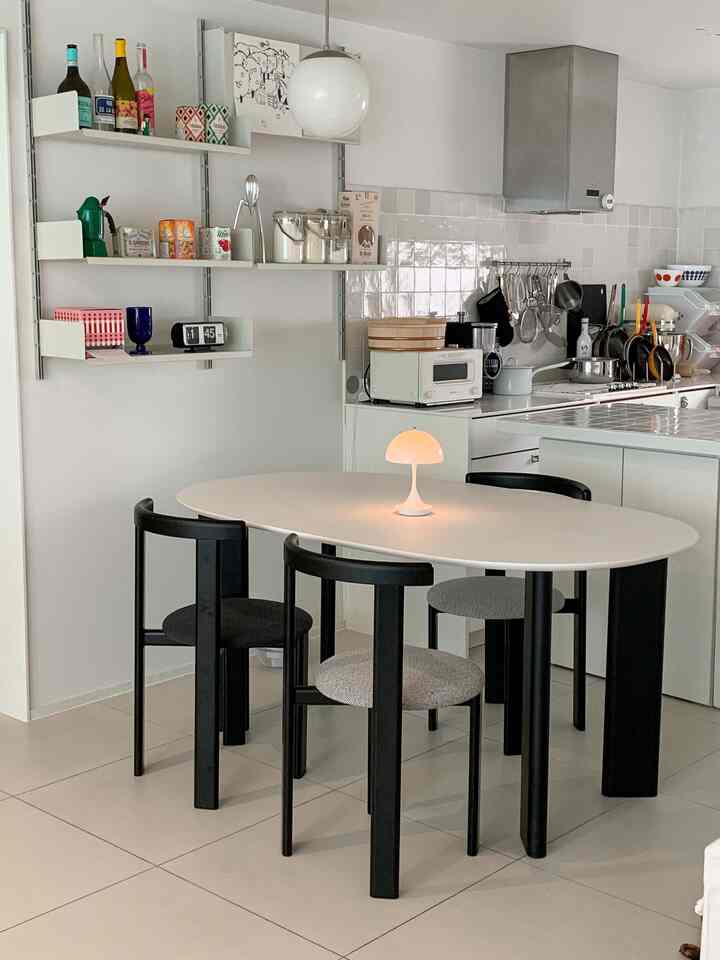 白と黒のトーンのキッチンスペース、アーティックセラミックのダイニングテーブルと黒い椅子が配置されたシンプルでモダンなインテリア