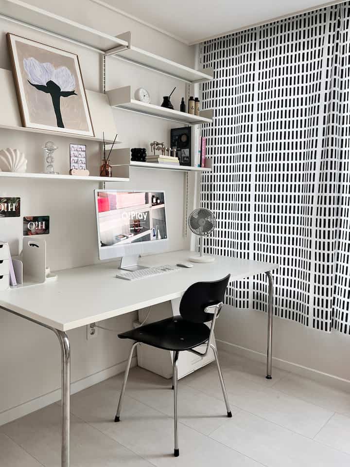 白黒のトーンでまとめられたコンパクトなホームオフィス、すっきりとしたデスクと椅子、壁の棚が配置されたシンプルモダンなインテリア